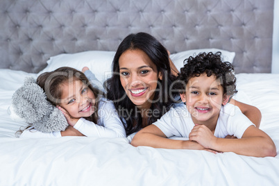 Smiling mother with children on the bed