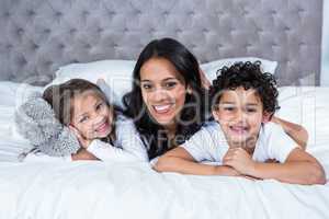 Smiling mother with children on the bed