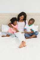 Mother and children reading in bed