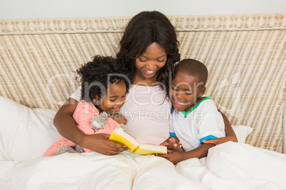 Mother and children reading book together