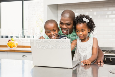 Father using laptop with his children in kitchen