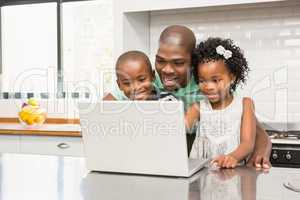 Father using laptop with his children in kitchen