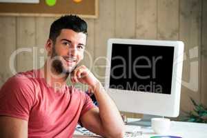 Smiling hipster sitting at his desk