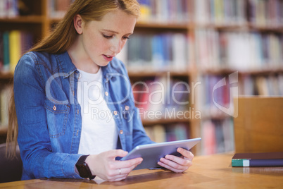 Student with smartwatch using tablet in library