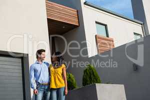 Happy couple standing in front of new house