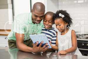 Father using tablet with his children in kitchen