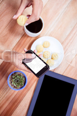 Overhead of feminine hands using smartphone and biscuit