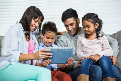 Smiling family on the sofa using tablet