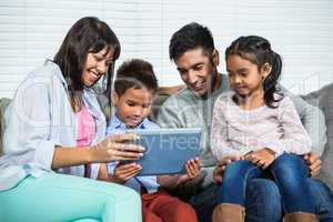 Smiling family on the sofa using tablet