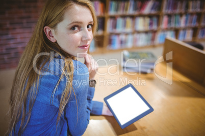 Student using tablet in library looking back at the camera