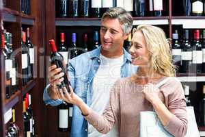 Smiling couple looking at bottle of wine