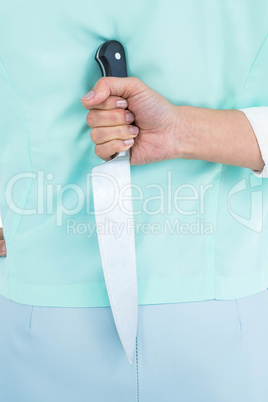Rear view of businesswoman hiding knife in her back