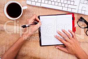 Businesswoman writing on diary on desk