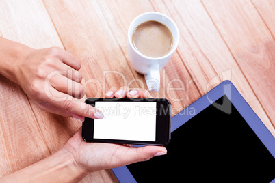 Businesswoman using her smartphone on desk