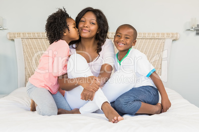 Mother and children sitting on bed