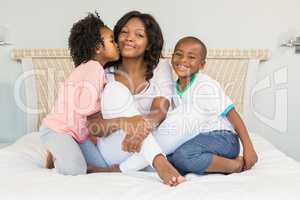Mother and children sitting on bed