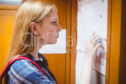 Pretty student looking at notice-board