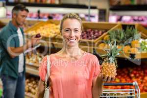 Smiling woman holding a pineapple