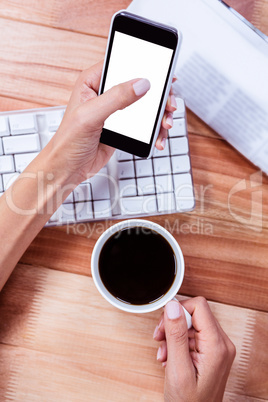 Businesswoman holding smartphone and coffee cup
