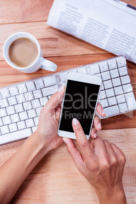 Businesswoman using her smartphone on desk