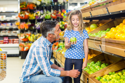 Cute child holding a green apple in the grocery shop