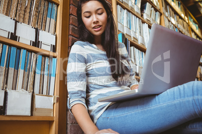 Smiling student sitting on the floor against wall in library stu