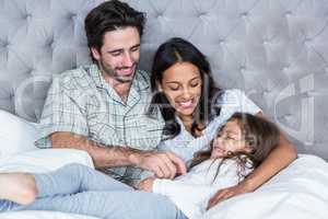 Happy parents tickling daughter