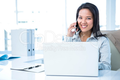 Smiling businesswoman phoning at the desk