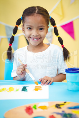 Smiling girl with a paintbrush in her hand