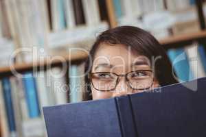 Pretty student hiding face behind a book