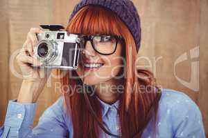 Smiling hipster woman taking pictures with a retro camera