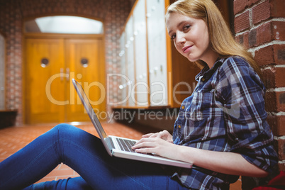 Focused student sitting on the floor against the wall using lapt Focused student sitting on the floor against the wall using lapt