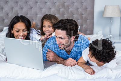 Happy family using laptop on bed