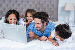 Happy family using laptop on bed