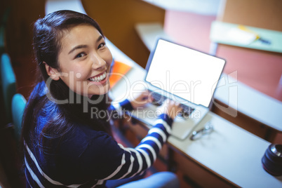 Happy student in lecture hall using laptop