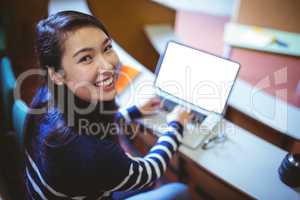 Happy student in lecture hall using laptop