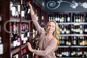 Smiling woman picking bottle of wine