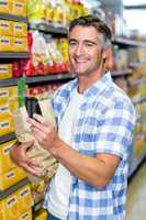 Smiling man with grocery bag using smartphone