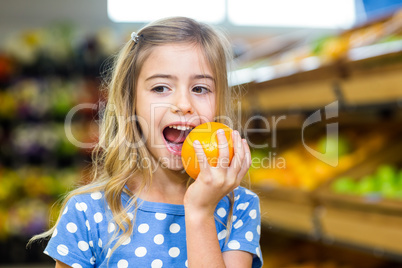 Smiling young girl eating an orange