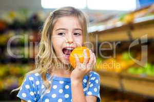 Smiling young girl eating an orange