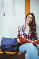 Smiling student sitting and reading a notebook