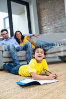 Smiling family in living room with son drawing