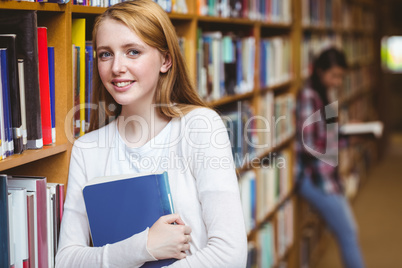Smiling student leaning against bookshelves