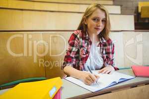 Smiling student taking notes during class