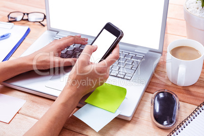 Feminine hands using smartphone and laptop