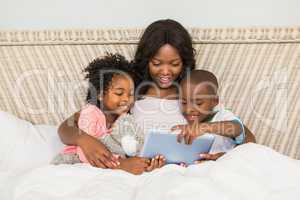 Happy family using tablet in bed