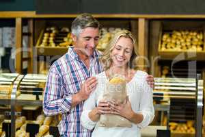 Smiling couple holding bread in paper bag