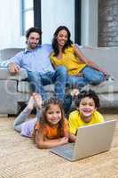 Children laying on carpet in living room using laptop