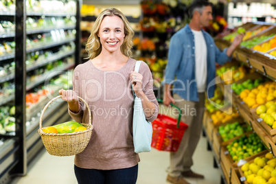 Pretty blonde woman holding vegetables basket