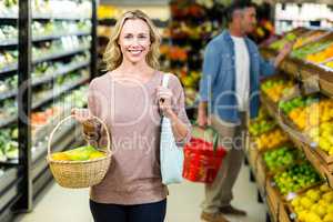Pretty blonde woman holding vegetables basket